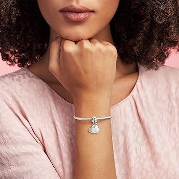 Pandora ハートの留め金とチャームが付いたスターリングシルバーのバングル。 Pandora ハートの留め金とチャームが付いたスターリングシルバー